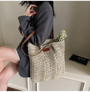Detail of hand-woven straw tote with brown leather straps and YELIYA label