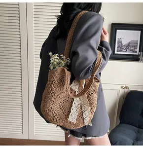 Detail of hand-woven brown crochet tote bag with white lace bow and floral accent