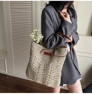Detailed close-up of handmade woven straw tote with brown leather strap and YELIYA branding