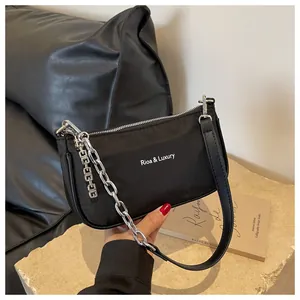 Close-up of black nylon shoulder bag with silver metal chain and logo detail
