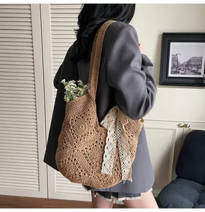 Detail of a brown crochet tote bag with flower patterns and white lace ribbon bow