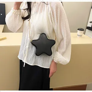 Détail d'un sac bandoulière noir en forme d'étoile avec chaîne dorée en décor quotidien