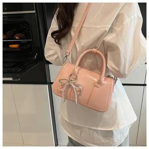 Rosa Lackleder-Boston-Tasche mit Perlen-Schleifen-Anhänger als Umhängetasche getragen