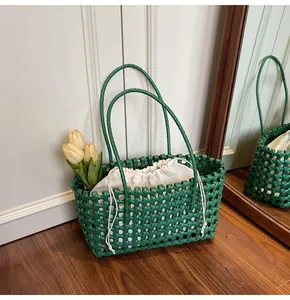 Detail of green woven hollow tote bag with a white drawstring lining on wooden floor