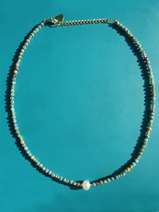 Detailed shot of colorful gemstone and pearl beaded necklace with gold heart charm clasp