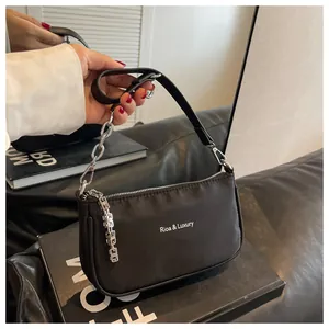Detail view of the silver metal chain and white brand logo on a black nylon baguette bag