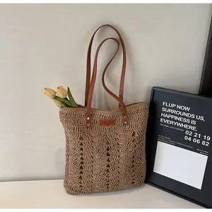 Detail of woven straw tote bag with brown leather straps and branded YELIYA leather patch