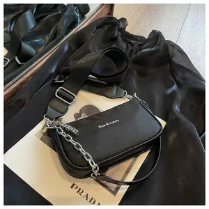 Detail of black nylon shoulder bag with adjustable strap and silver metal chain accessory