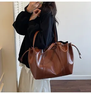 Detail of dark brown leather bucket bag with drawstring closure and glossy finish