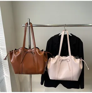 Close-up of brown and pink tote bags with bow detail and drawstring on a metal hanger