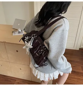 Detail view of burgundy patent leather shoulder bag with silver star and dog charms
