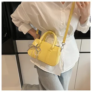 Nahaufnahme der gelben Boston Bag mit elegantem Anhänger aus silbernen Perlen und Schleife