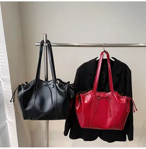 Close-up of glossy PU leather tote bag featuring a decorative bow and side drawstring detail