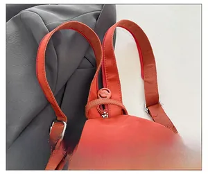 Close-up of orange nylon backpack with double handles, wide straps and metal buckles