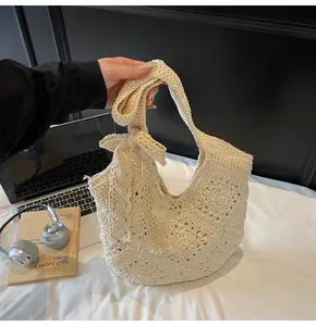 Detail of hand-woven off-white shoulder bag featuring a lace bow and crochet texture