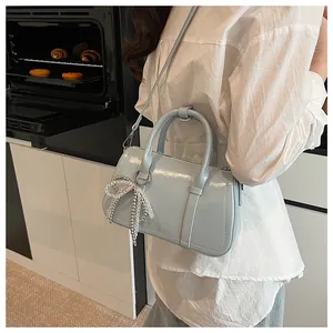 Detail der hellblauen Boston Bag mit glänzendem Finish und Perlen-Schleifen-Anhänger in Küche