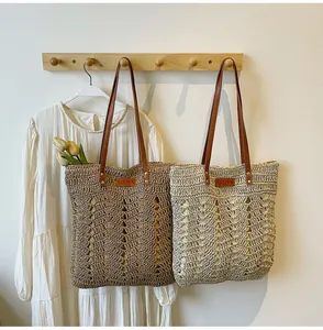 Detail of hollow-out straw tote bags with leather handles and YELIYA logo label