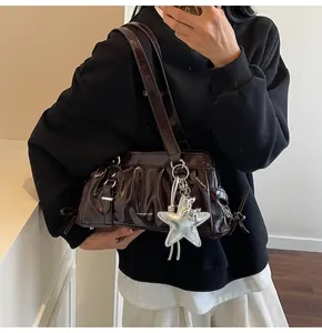Macro shot of dark brown patent leather shoulder bag with star charm and ribbon detail