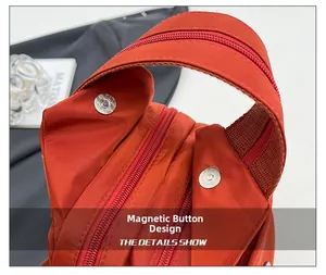 Detail view of brick red nylon backpack featuring magnetic buttons and dual zipper design