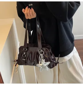 Detail of glossy brown shoulder bag with pleated texture and silver star pendant
