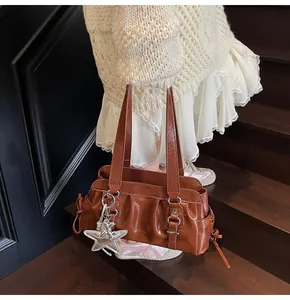 Close-up of brown glossy patent leather shoulder bag with pleats and star charm