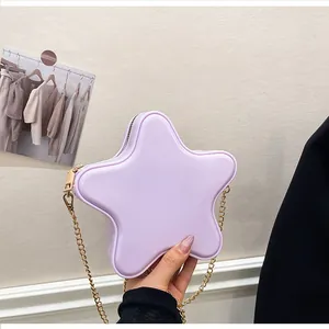 Gros plan du sac bandoulière étoile lavande avec chaîne dorée tenu à la main