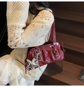 Detail of wine red glossy patent leather shoulder bag with silver star charm accessory
