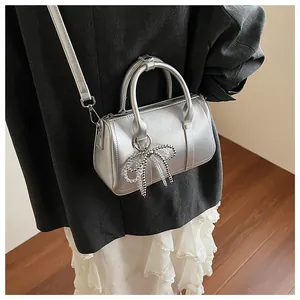 Detail der silbernen Boston Bag mit Perlenbogen und Metallic-Finish am Modell