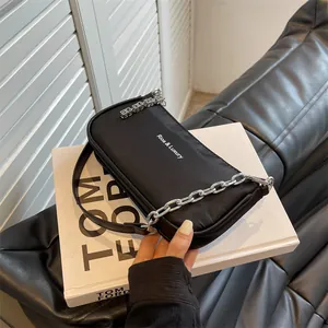 Minimalist black nylon baguette bag with silver metal chain and leather strap details