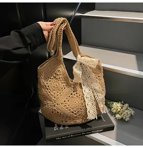 Detail of hand-woven crochet tote bag featuring floral patterns and a lace bow accent