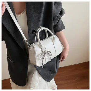 Nahaufnahme der weißen Boston-Handtasche mit Perlen-Schleife an einem Model in Spitze