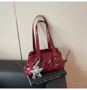 Detail of burgundy ruched faux leather shoulder bag with star charm and vintage texture