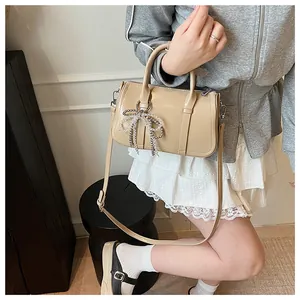 Detail der apricotfarbenen Boston Bag mit Perlen-Schleifen-Anhänger und Umhängegurt