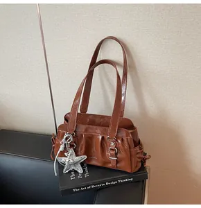 Detail of pleated brown shoulder bag with silver star pendant on black books