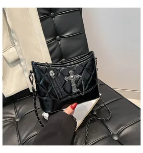 Detalle de bolso hobo acolchado negro con colgantes de cruz y calavera plateados