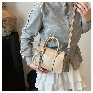 Nahaufnahme der cremefarbenen Boston-Tasche mit dekorativer Perle und verstellbarem Gurt