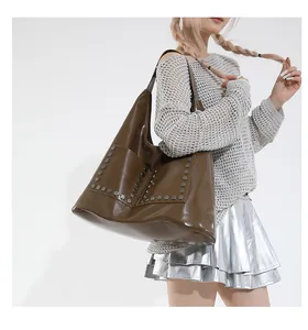 Detail of glossy brown leather tote bag with silver hexagonal rivets and front pockets