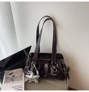Detail of dark brown glossy leather shoulder bag with vintage star charm and pleats