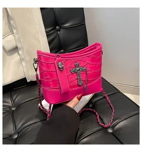 Detalle de bolso rosa con relieve de cocodrilo con cruz de metal y dije de calavera