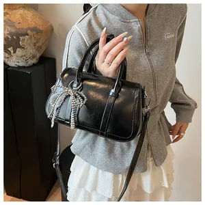 Detail der schwarzen Lackleder-Boston-Tasche mit weißem Perlenbogen und Schultergurt