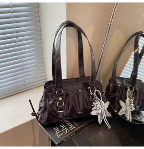 Detail of dark brown patent leather bag with pleats and silver star pendant