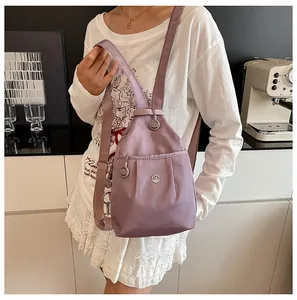 Detail of purple nylon backpack with metal logo and adjustable straps on model