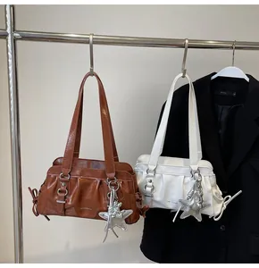 Close-up of pleated leather shoulder bags in brown and beige with metal star charms