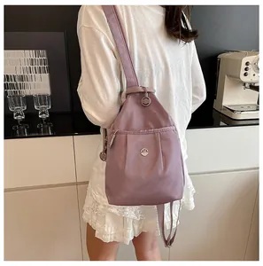 Close-up of lavender nylon backpack featuring a metallic M logo and stylish pleated texture