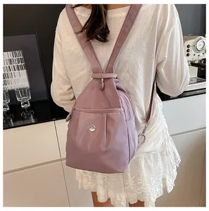 Detail view of a lightweight purple nylon mini backpack worn in a stylish cafe setting