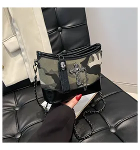 Detalle del bolso de lona camuflaje con cruz plateada, dije de calavera y cadena de metal