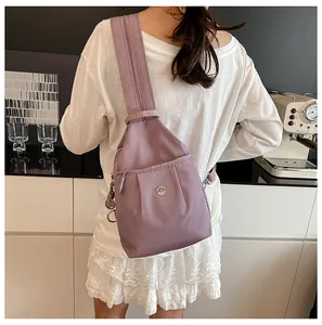 Back view of woman wearing a lilac nylon crossbody bag with metallic M logo in a kitchen