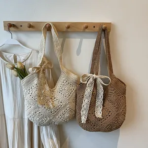 Handmade crochet shoulder bag with floral patterns and lace ribbons for beach vacations