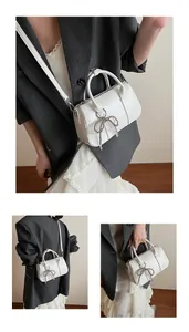 Detail der cremeweißen Boston Bag mit Perlen-Bogen-Anhänger und silbernen Beschlägen