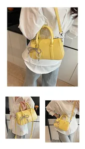 Nahaufnahme einer gelben Boston Tasche mit Perlen-Schleifenanhänger und glatter Textur